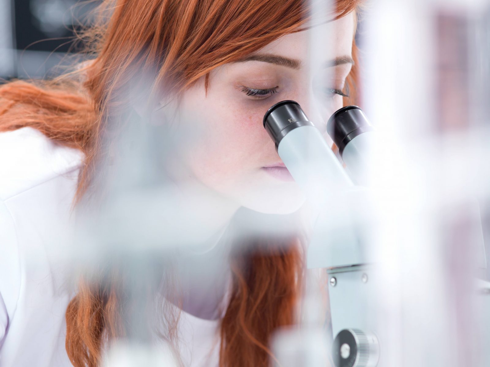 Woman in lab looking through a microscope