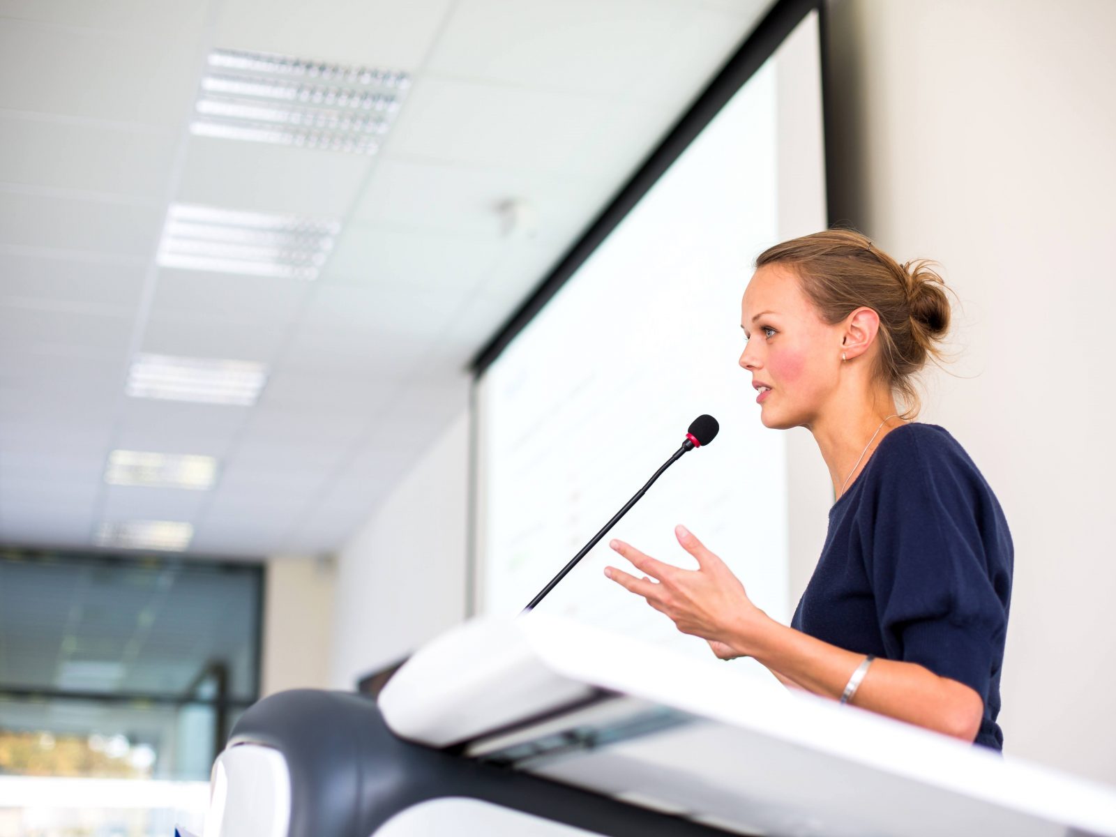 Female stood at lectern presenting to delegates at a conference