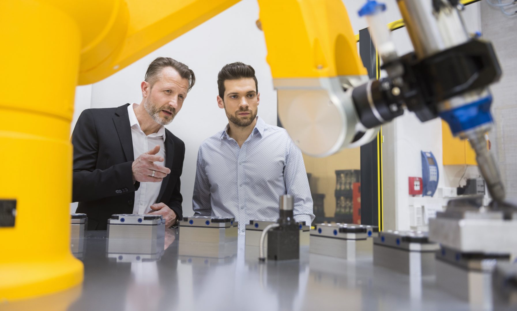 Two men working in laboratory with a robotic arm